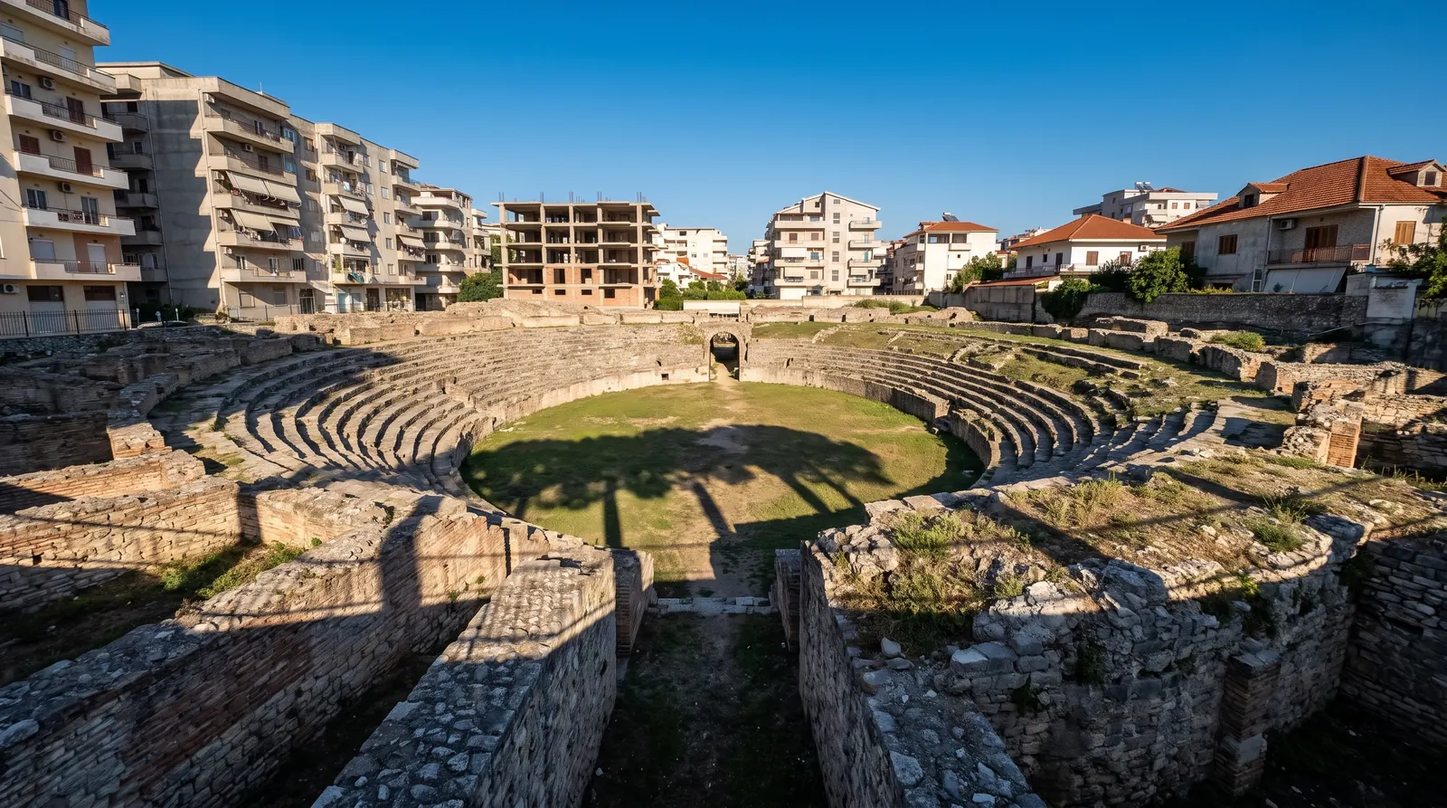 The Roman amphitheatre of Durres in its pit, houses and apartment blocks pressed to the rim on every side