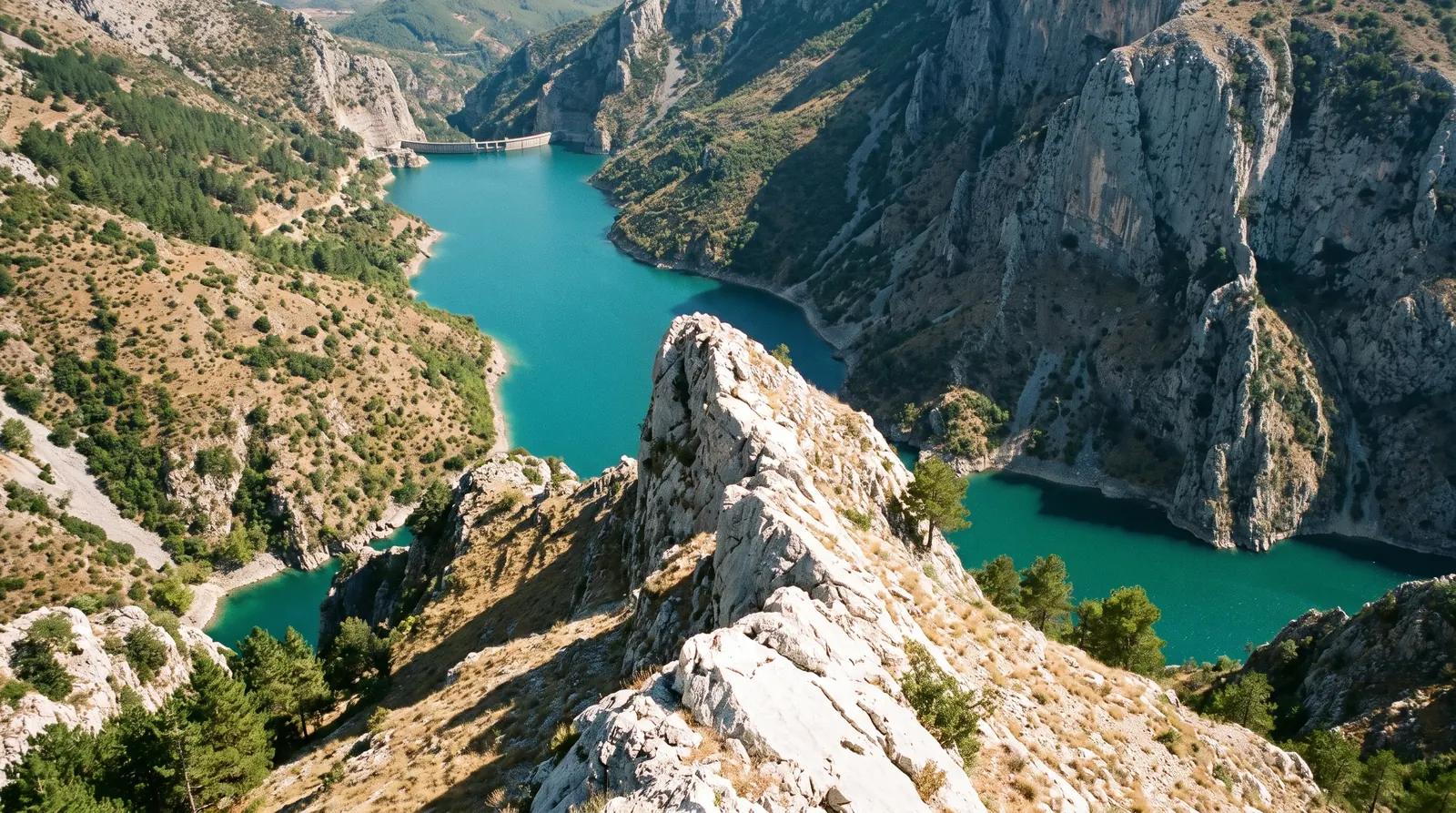 The rock prow of Gamti above the narrow turquoise water of the Bovilla reservoir