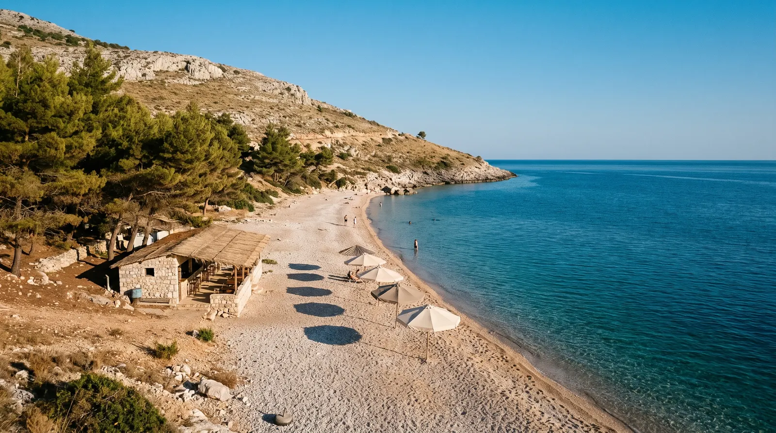 The quiet pebble beach at Lukove, one low building and a handful of umbrellas